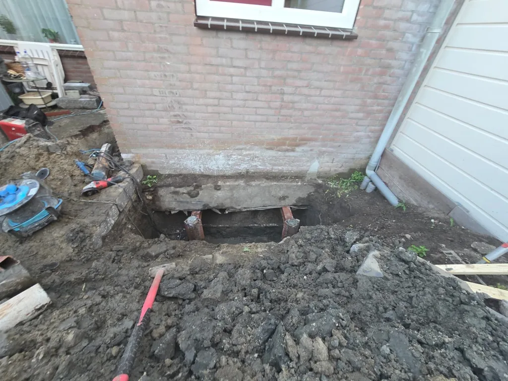 Consolepalen bij een aanbouw: twee consoles onder de fundering, gedragen door stalen buispalen in de ontgraving langs de gevel