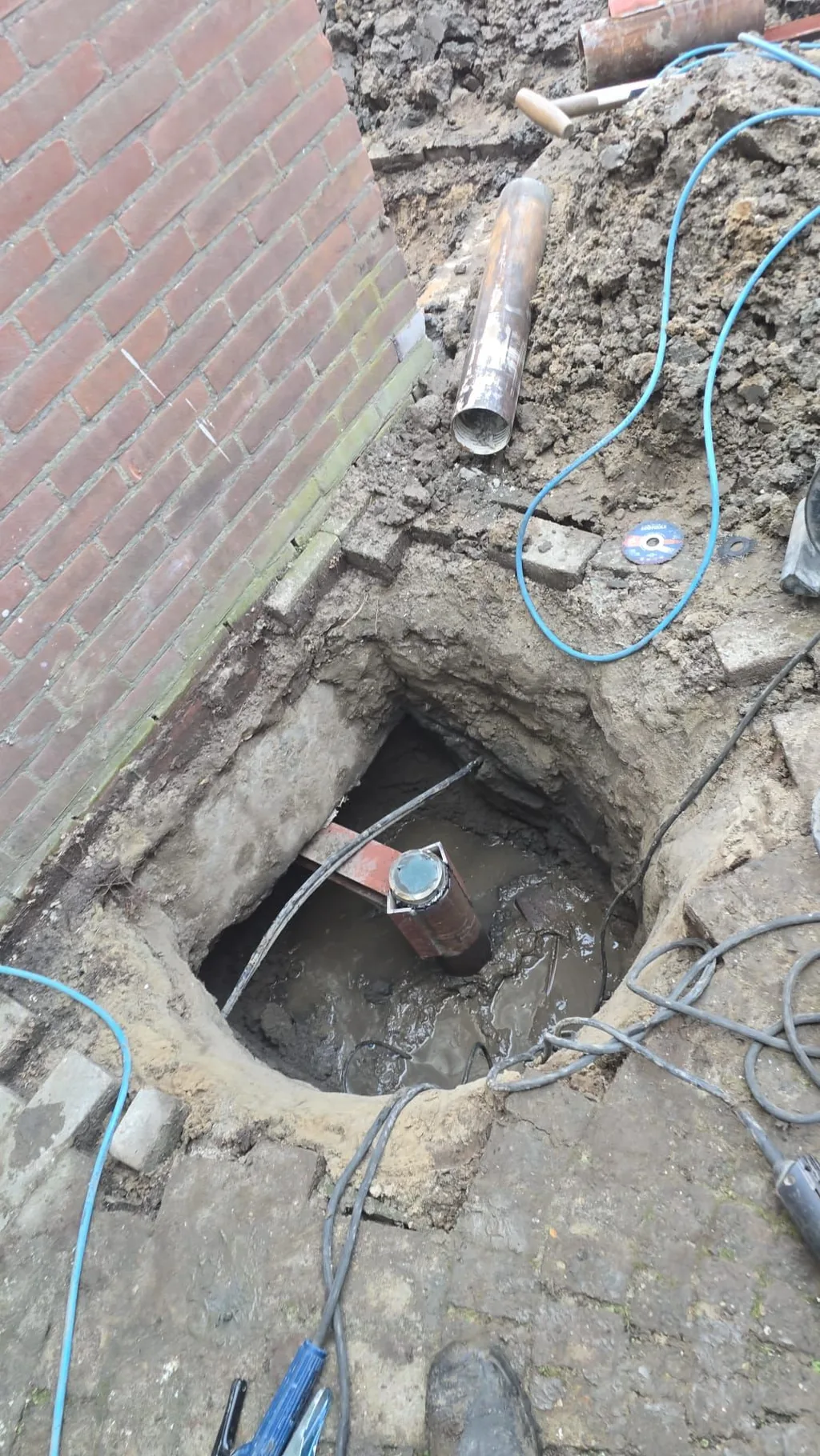 Console geplaatst over de paalkop van een consolepaal, met het draagvlak onder de bestaande fundering in de ontgraving naast de gevel