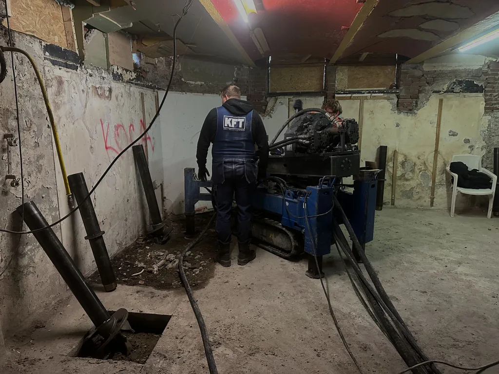 Compacte boormachine van KFT boort schroefinjectiepalen voor funderingsherstel in een souterrain in Zaandam
