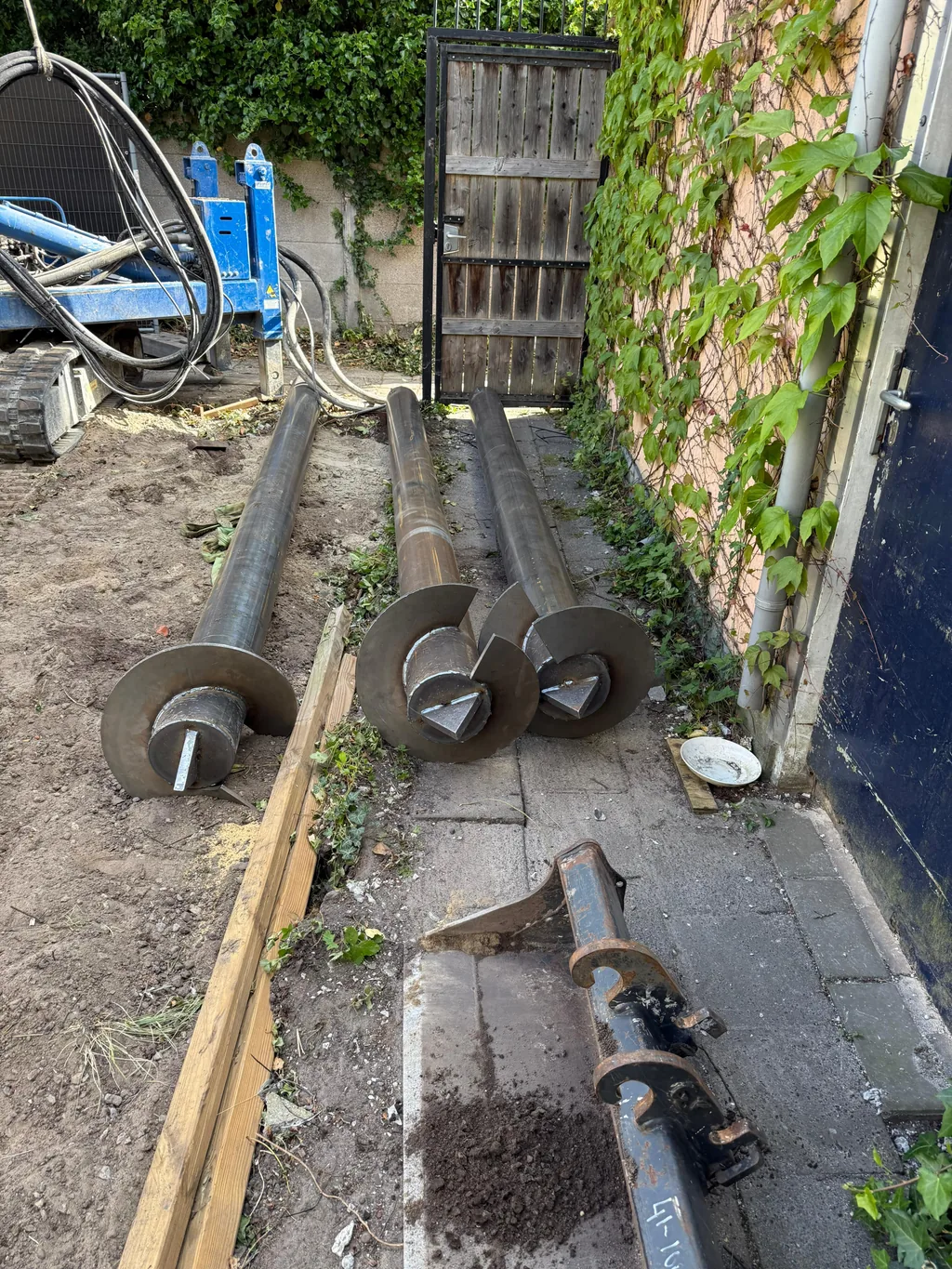 Stalen paalbuizen met schroefpunt liggen klaar naast de boorstelling bij een woninguitbouw in Breda