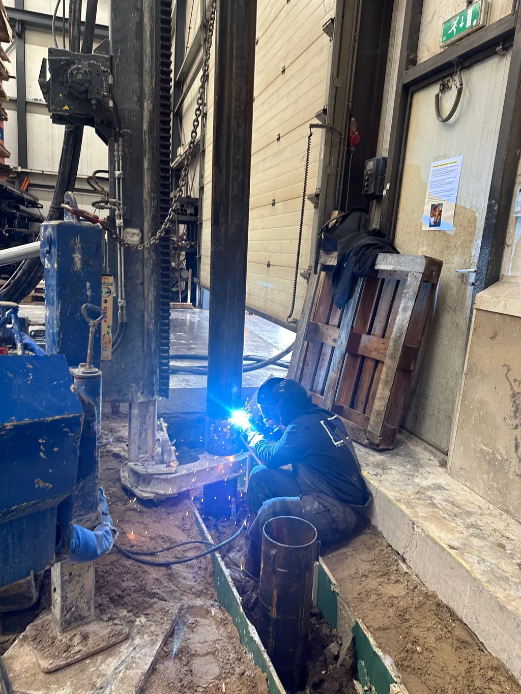 Lasser aan het werk aan een stalen buis van een casing draaipaal onder de boorstelling in Enkhuizen