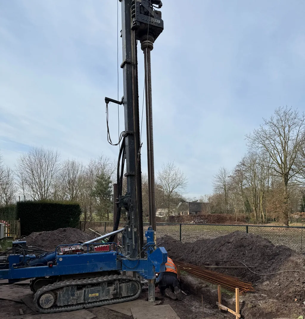 Medewerker aan de voet van de boormast tijdens het boren van casing draaipalen in Essen, België