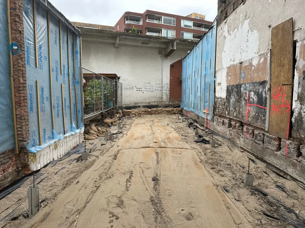 Afgewerkte paalkoppen van casing draaipalen langs de belendende gevels op de bouwkavel in Rotterdam
