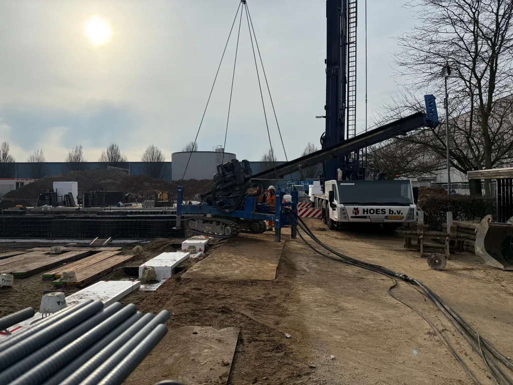 Boorstelling voor casing draaipalen hangt aan de hijsbanden van een kraan op het bouwterrein in Sittard