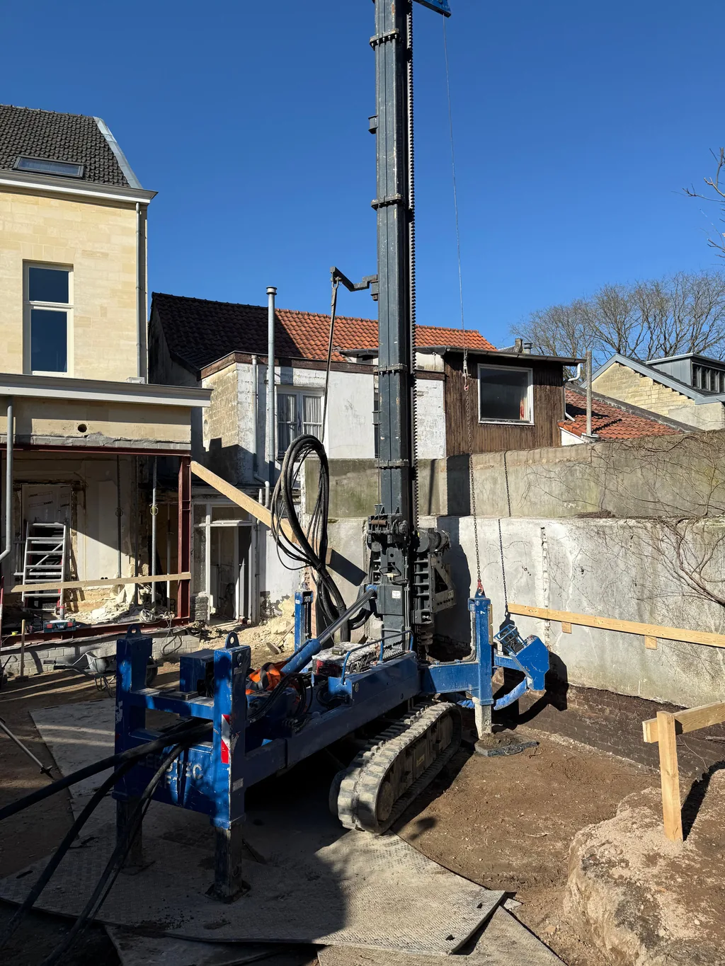 Blauwe boorstelling voor casing draaipalen in een bouwput achter een woning in Valkenburg