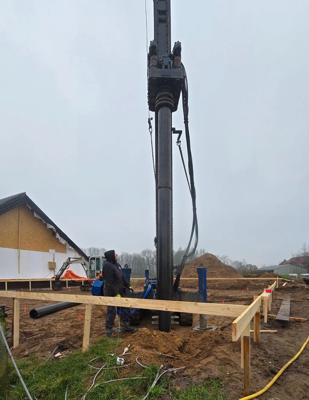 Medewerker kijkt omhoog langs de boormast bij het boren van een casing draaipaal in Zwolle
