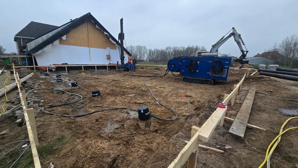 Bouwterrein in Zwolle met boorstelling, groutinstallatie en graafmachine tijdens het boren van casing draaipalen