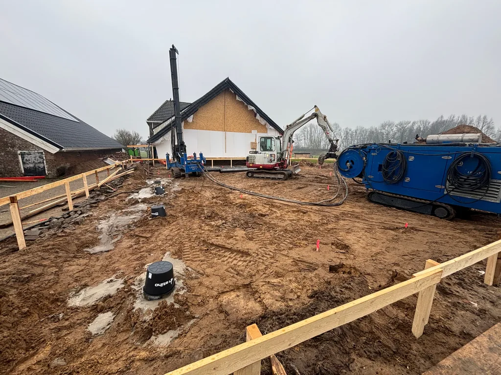 Afgedekte paalkoppen van casing draaipalen op het bouwterrein in Zwolle, met graafmachine en boorstelling