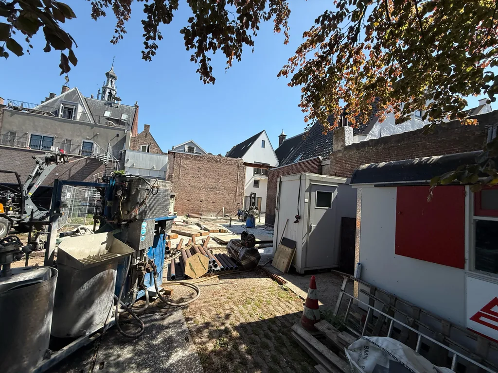 Bouwplaats in het centrum van Culemborg met groutinstallatie, paalbuizen en bouwketen tussen historische panden