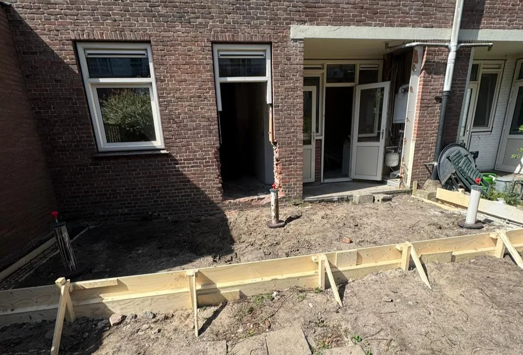 Houten bekisting en schroefinjectiepalen in een achtertuin in Amsterdam voor de fundering van een uitbouw