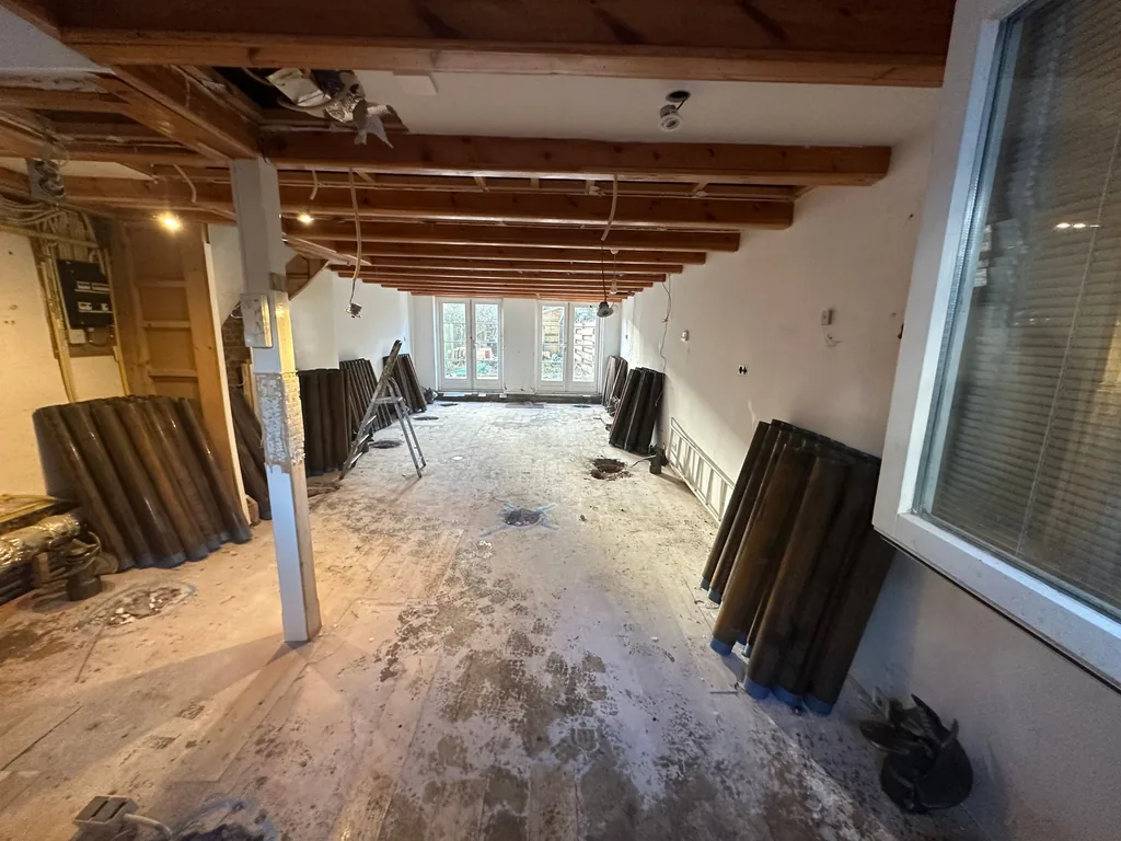 Leeggemaakte begane grond aan de Oetewalerstraat in Amsterdam met stapels paalbuizen voor de schroefinjectiepalen