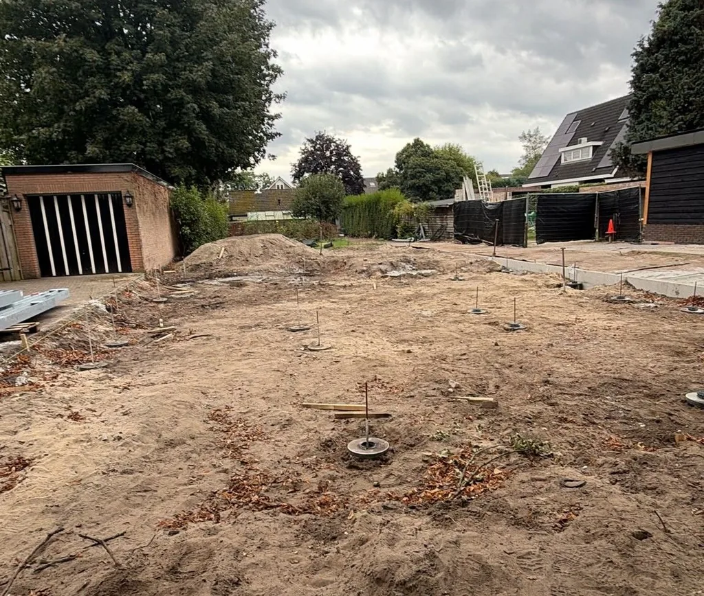 Bouwkavel in Apeldoorn met de paalkoppen en stelplaatjes van 20 aangebrachte schroefinjectiepalen Ø 114 mm, tussen bestaande woningen