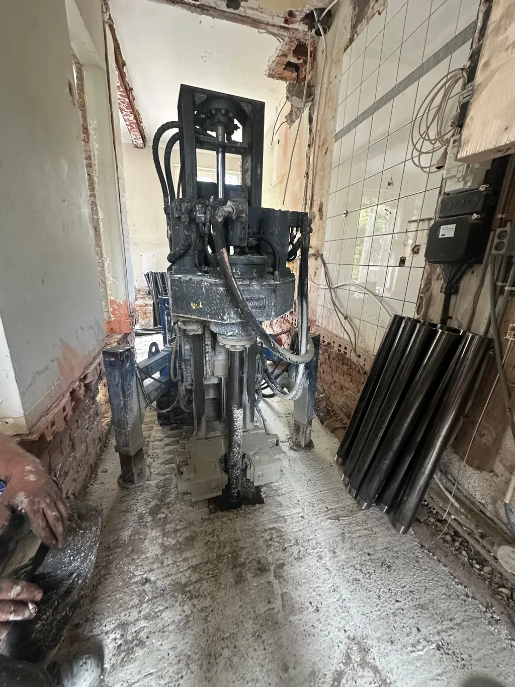Boorstelling in een smalle ruimte van een woning in Duivendrecht, met buizen voor schroefinjectiepalen tegen de wand