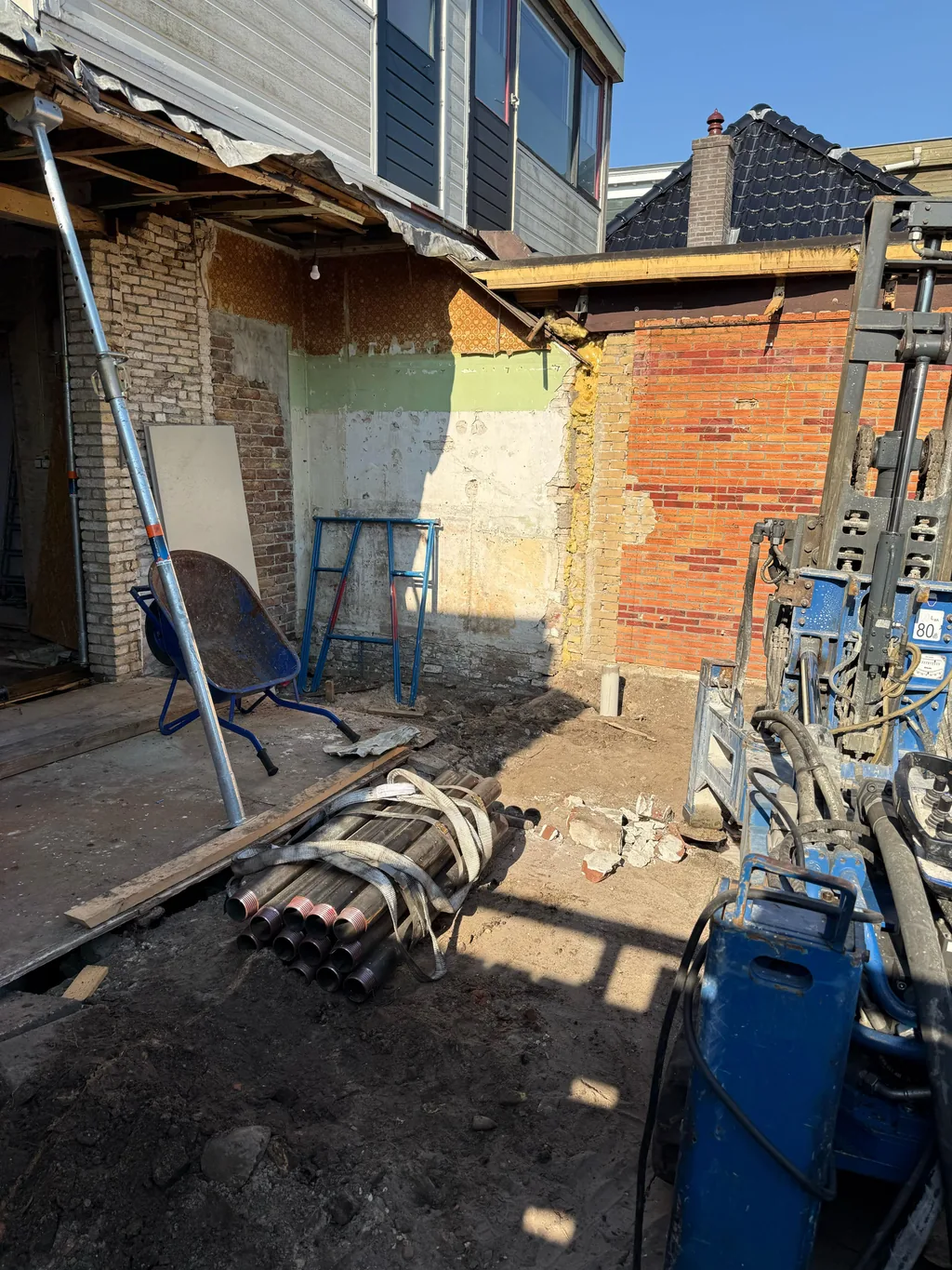 Boorstelling en een gebundelde stapel paaldelen voor schroefinjectiepalen bij de uitbouw van een woning in Heerenveen