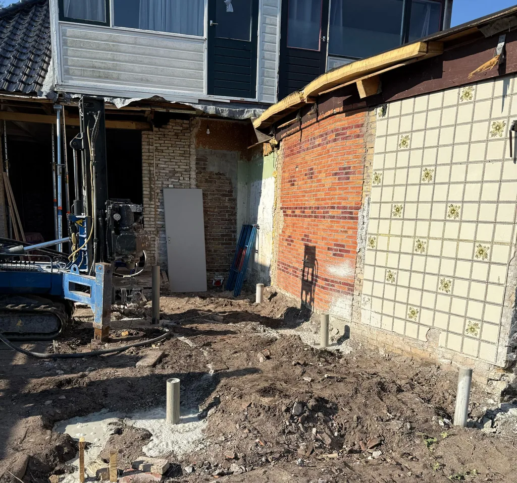 Uitstekende paalkoppen van schroefinjectiepalen naast de gevel van een woning in Heerenveen, met boorstelling links