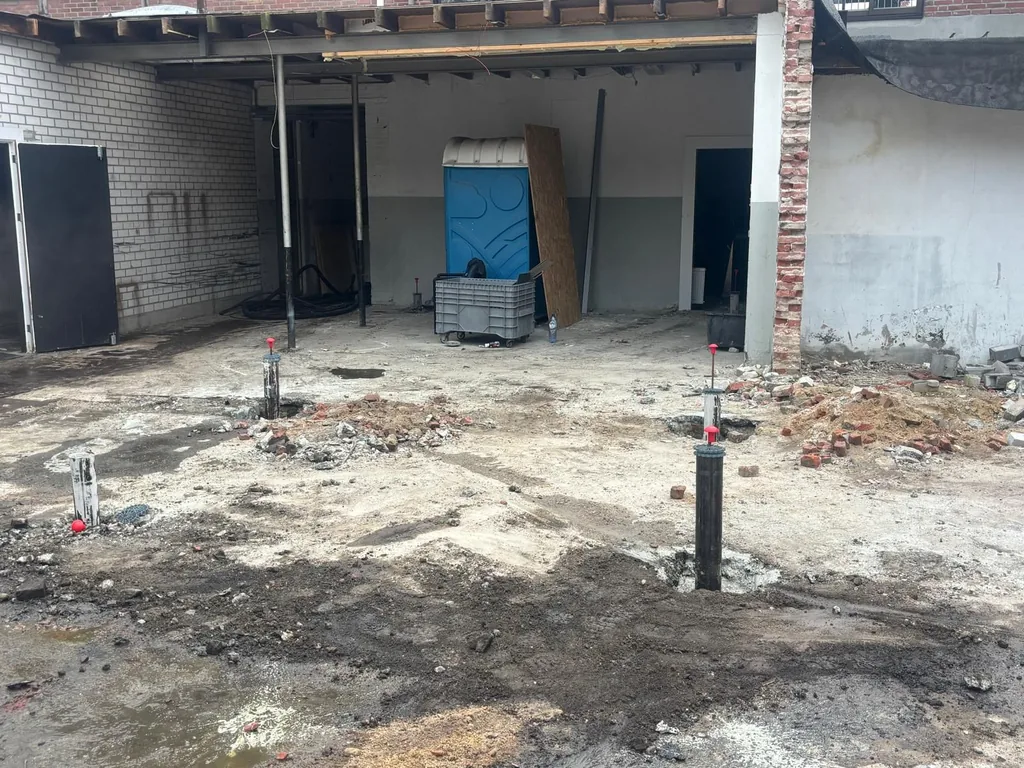 Binnenplein in Helmond met aangebrachte schroefinjectiepalen Ø 114 mm, gemarkeerd met rode piketten, tegen het bestaande pand waar 7 appartementen komen