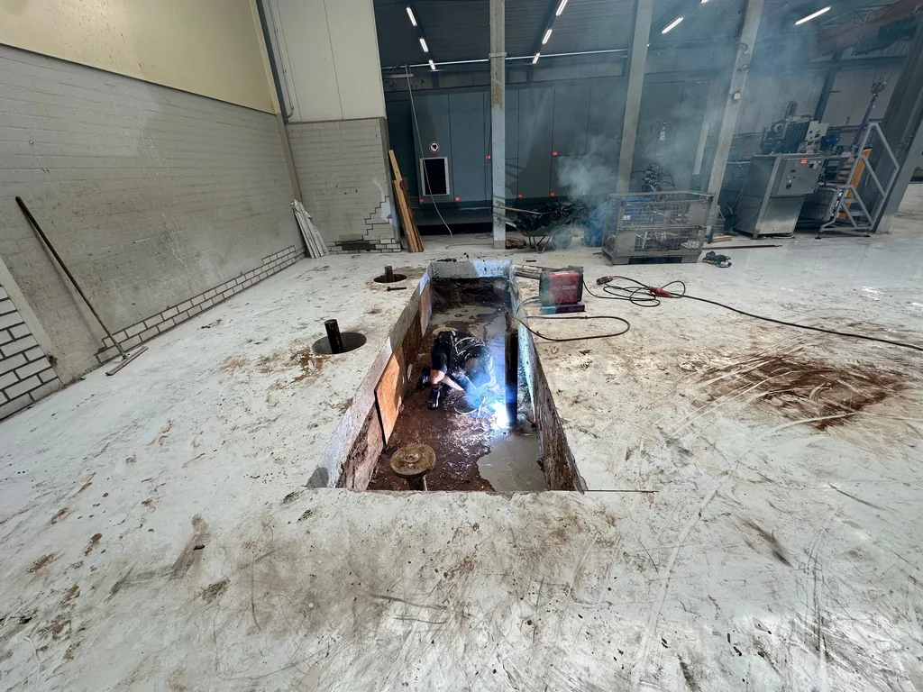 Uitgegraven funderingsput in de fabrieksvloer in Helmond waar een medewerker last, voor de machinefundering op schroefinjectiepalen