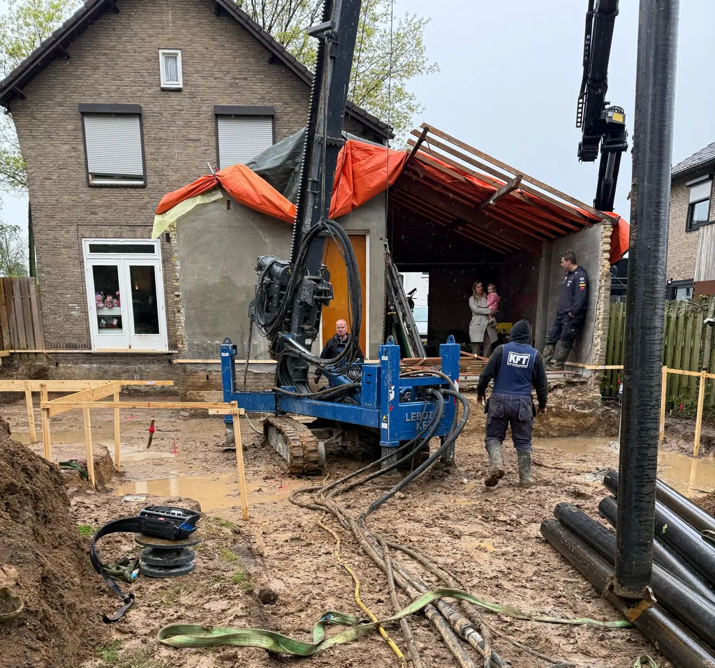 Boorstelling voor schroefinjectiepalen voor de ruwbouw van een woninguitbouw in Hensbroek, met stalen buizen op de voorgrond