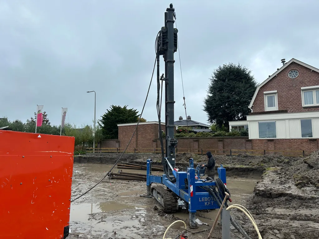 Boorstelling voor schroefinjectiepalen in een modderige bouwput na hevige regen in Honselersdijk