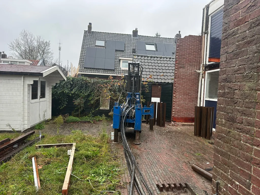 Boorstelling voor schroefinjectiepalen in een smalle achtertuin tussen tuinhuis en woning in Hoofddorp