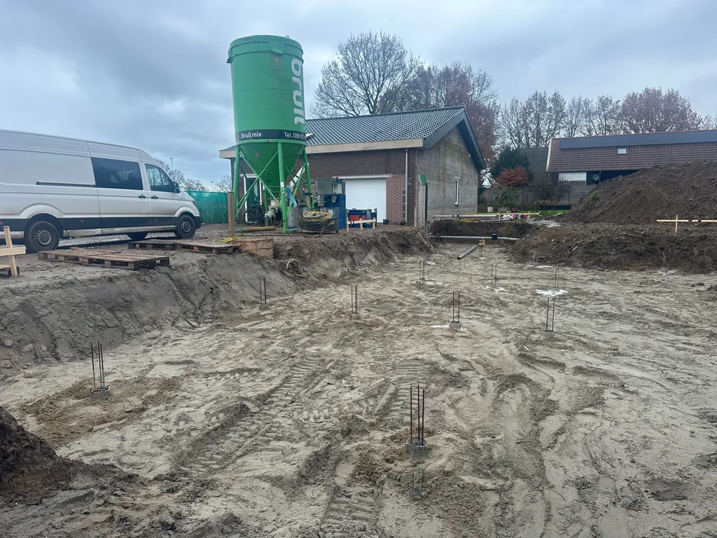 Bouwput in Houten met paalkoppen van schroefinjectiepalen, wapeningsstaven en een groutsilo op de achtergrond