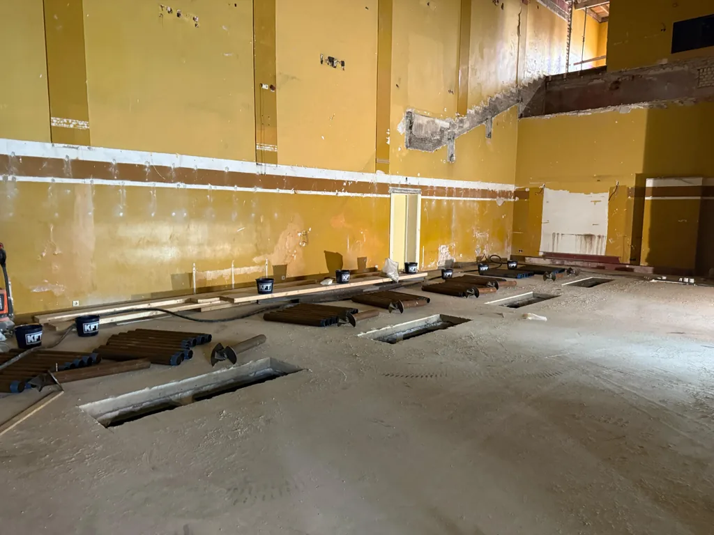 Vloersparingen en klaarliggende paalbuizen langs de wand van de zaal in het Thalia Theater in IJmuiden