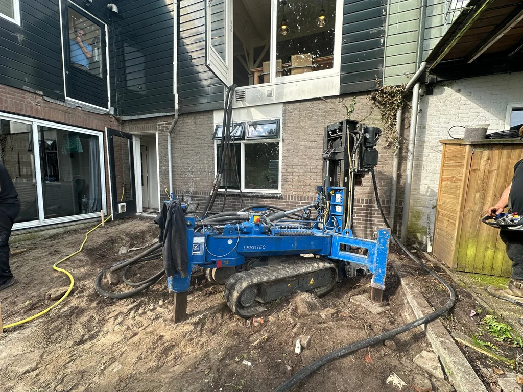 Blauwe boorstelling voor schroefinjectiepalen in de achtertuin van een woning in Landsmeer