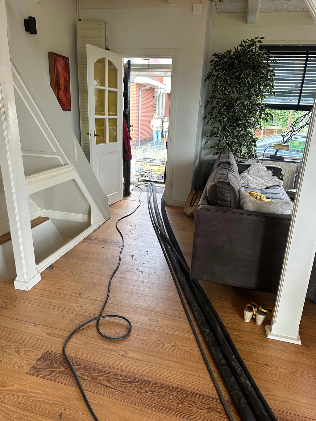Hydraulische slangen lopen door de woonkamer naar de achtertuin in Landsmeer, waar schroefinjectiepalen worden geboord