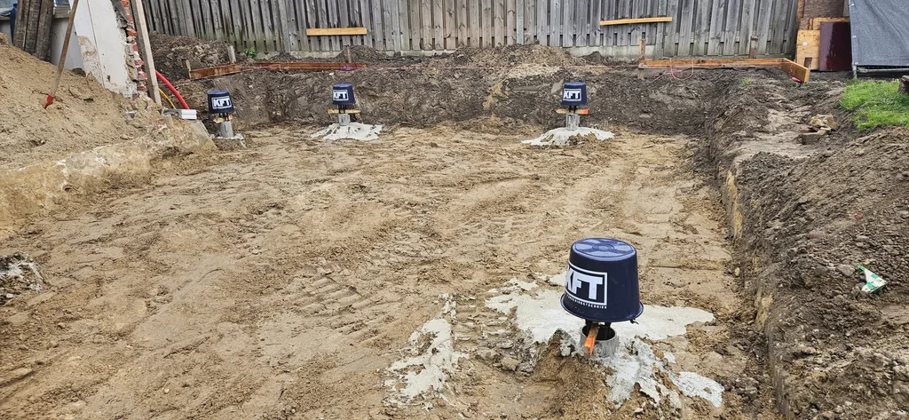 Afgedekte paalkoppen van schroefinjectiepalen met KFT-emmers in de uitgegraven bouwput van een uitbouw in Veldhoven