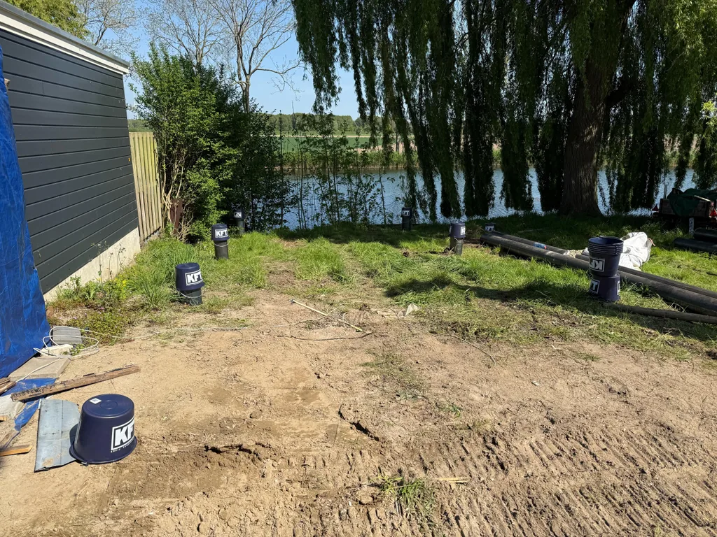 Geheide stalen buispalen met KFT-emmers op de paalkoppen in een tuin aan het water in Brielle
