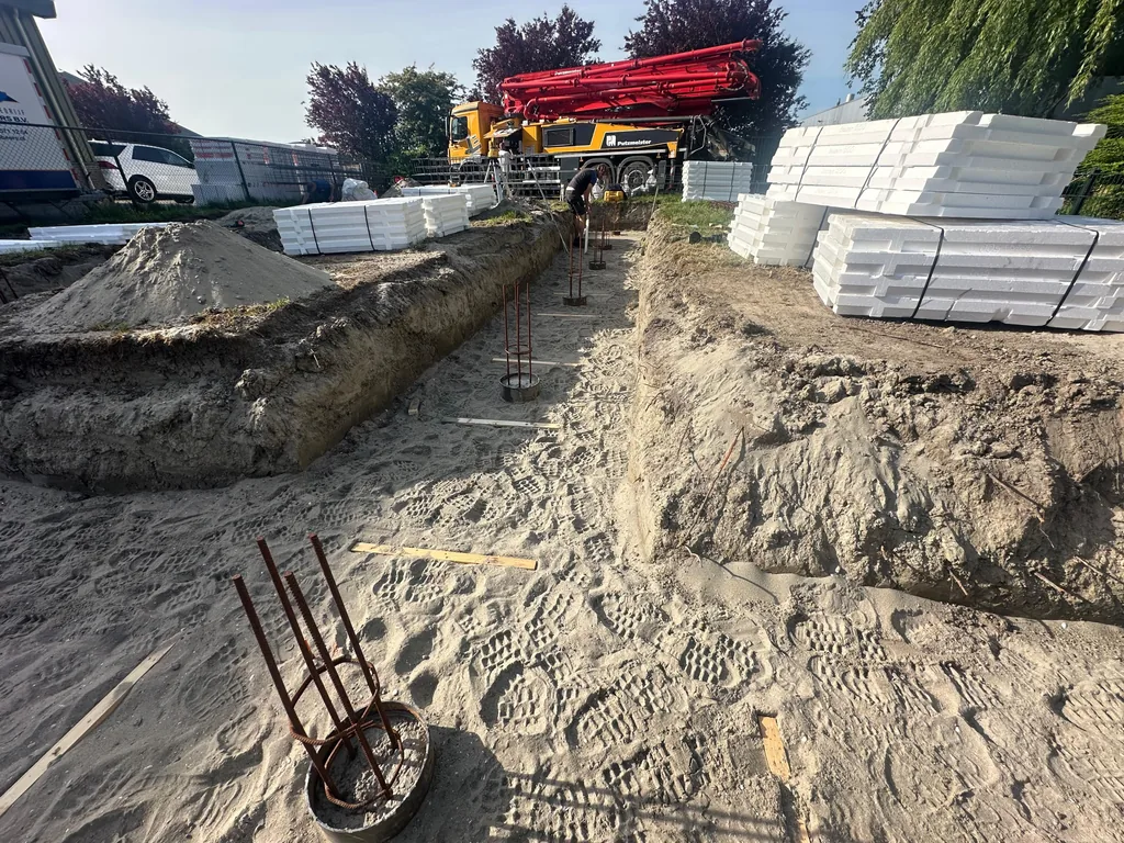 Wapeningskorven in de paalkoppen van stalen buispalen, met op de achtergrond een betonpomp, in Heerhugowaard
