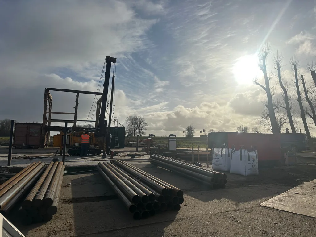 Heistelling en stapels stalen buispalen in tegenlicht op de bouwplaats van boerderij Stolp in Starnmeer